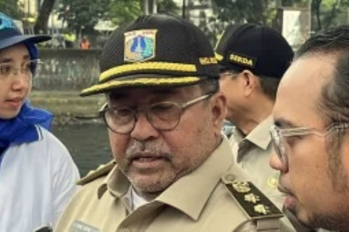 Rano Karno mengenakan baju safari cokelat, mengawasi pengerukan Kali Krukut menggunakan alat berat, sambil memberikan acungan jempol dan tersenyum. (Foto: Istimewa)