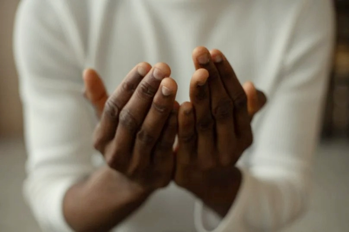 Foto: Ilustrasi berdoa dengan khusyuk di sekitar pusara, menciptakan suasana yang syahdu. Lalu, benarkah wanita dilarang ziarah kubur? Begini penjelasan Gus Baha. (Freepik)