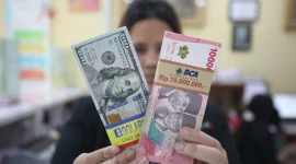 Seorang karyawan menunjukkan pecahan mata uang Rupiah dan Dolar AS di salah satu gerai penukaran valuta asing di Jakarta, Senin (3/3/2025). (Dok. Bisnis.com)