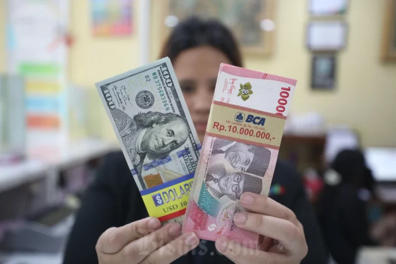 Seorang karyawan menunjukkan pecahan mata uang Rupiah dan Dolar AS di salah satu gerai penukaran valuta asing di Jakarta, Senin (3/3/2025). (Dok. Bisnis.com)