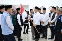 Wakil Gubernur Banten, A Dimyati Natakusumah, secara simbolis menyerahkan bendera Merah Putih kepada perwakilan jemaah haji Kloter 57-JKG. (Dok. Biro Adpimpro Banten). 