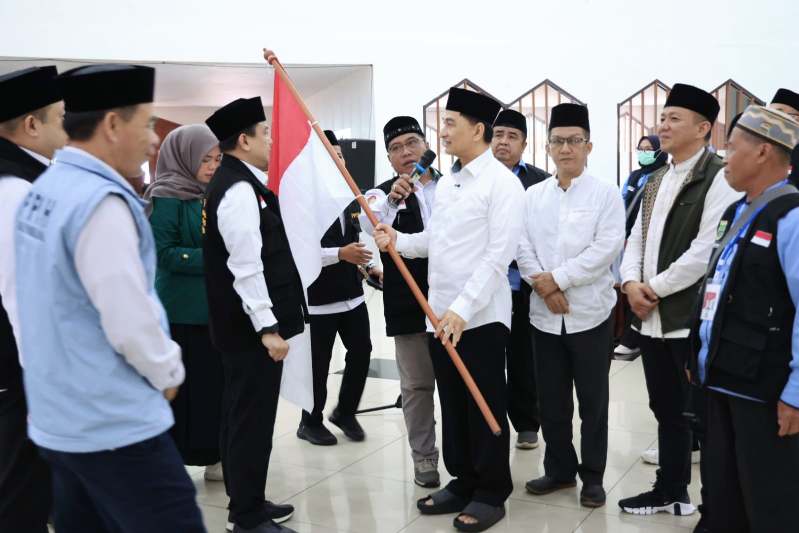 Wakil Gubernur Banten, A Dimyati Natakusumah, secara simbolis menyerahkan bendera Merah Putih kepada perwakilan jemaah haji Kloter 57-JKG. (Dok. Biro Adpimpro Banten). 