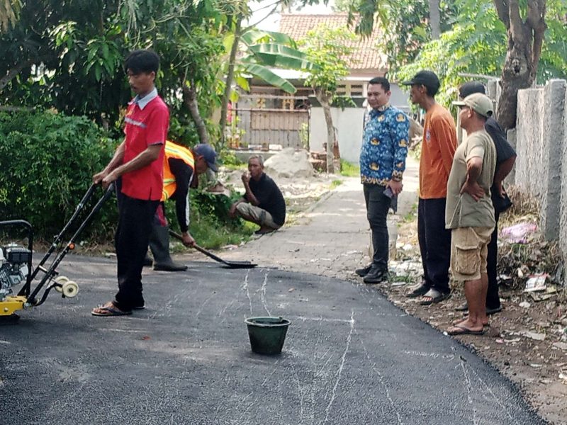 Foto: Kepala Desa Karang Anyar, Suhendri (berbaju batik biru), meninjau langsung proses pengerjaan jalan hotmix yang bersumber dari Dana Desa. (Dok. Ahmad/Metrosiar). 