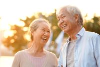 senior asian couple enjoying good time outdoors in park at dusk, happy and smiling