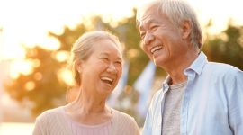 senior asian couple enjoying good time outdoors in park at dusk, happy and smiling