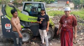 Foto: Tiga warga Benyawakan Jaya berfoto di depan alat berat loader bantuan PT Haleyora Powerindo (HPI) dan PT Indonesia Power (IP) yang digunakan untuk membersihkan lahan perluasan. (Dok. IRMAS Baiturrahim Beyawakan Jaya) 