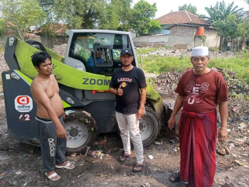 Foto: Tiga warga Benyawakan Jaya berfoto di depan alat berat loader bantuan PT Haleyora Powerindo (HPI) dan PT Indonesia Power (IP) yang digunakan untuk membersihkan lahan perluasan. (Dok. IRMAS Baiturrahim Beyawakan Jaya) 