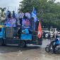 Massa buruh menggelar aksi unjuk rasa dengan mobil komando di ruas jalan Serang, membawa spanduk tuntutan penetapan UMK dan UMSK 2026, di bawah pengawalan aparat keamanan.