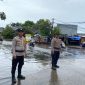 Personel Polsek Pasar Kemis melakukan pemantauan genangan air di Jalan Raya Kutabumi, Kabupaten Tangerang, guna memastikan arus lalu lintas tetap aman saat hujan deras.