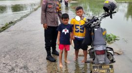 Bhabinkamtibmas Polsek Pasar Kemis memantau genangan air di jalan penghubung Kendal Karet–Sukatani, memastikan akses warga tetap aman dilalui meski hujan deras.