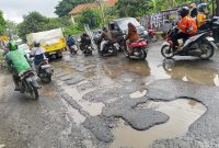 Jalan Raya Pasar Kemis rusak parah dan dipenuhi lubang besar yang tergenang air. Pengendara motor harus ekstra hati-hati saat melintas karena licin dan rawan kecelakaan.