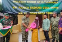 Dandim 0510/Tigaraksa, Letkol Inf Yudho Setyono, S.H., menyerahkan kunci rumah secara simbolis kepada warga penerima manfaat program rehabilitasi rumah tidak layak huni di Kampung Ranca Sadang, Desa Tapos, Jumat (23/01), dalam rangka HUT Korem 052/Wijayakrama ke-27.