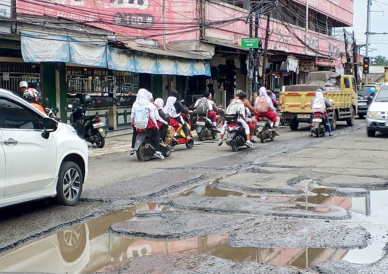 Sejumlah pelajar melintasi jalan rusak di kawasan Pasar Kemis, Kabupaten Tangerang, yang menjadi akses utama menuju sekolah setiap hari.