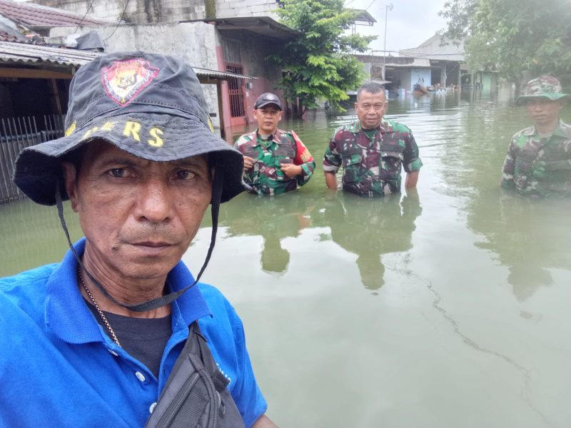 Jurnalis Metrosiar Alex Salembun (kaos biru) bersama Danramil Pasar Kemis Mayor Arm Sidik Abriyanto dan anggota TNI saat meninjau banjir yang merendam permukiman warga di RW 17 Vila Tomang Baru, Desa Gelam Jaya, Kecamatan Pasar Kemis, Kabupaten Tangerang, Minggu (08/03/2026).