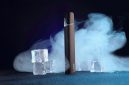 Perangkat rokok elektronik (vape) mengeluarkan uap di tengah latar es, menggambarkan tren penggunaan yang kini menjadi sorotan global terkait dampak kesehatan.