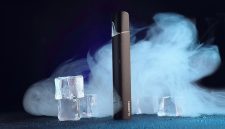 Perangkat rokok elektronik (vape) mengeluarkan uap di tengah latar es, menggambarkan tren penggunaan yang kini menjadi sorotan global terkait dampak kesehatan.