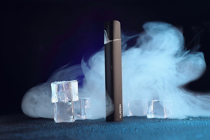 Perangkat rokok elektronik (vape) mengeluarkan uap di tengah latar es, menggambarkan tren penggunaan yang kini menjadi sorotan global terkait dampak kesehatan.