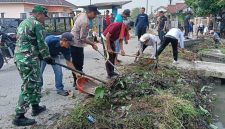 Personel TNI bersama aparat dan warga bergotong royong membersihkan tumpukan sampah dan rumput liar di saluran air kawasan Kampung Buaran Mangga, Kecamatan Pakuhaji.