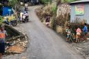Warga membantu pengendara melintasi tanjakan licin pascahujan di jalur menuju Pasar Agro, Enrekang.