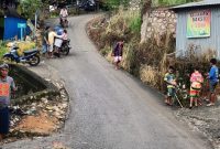 Warga membantu pengendara melintasi tanjakan licin pascahujan di jalur menuju Pasar Agro, Enrekang.