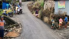 Warga membantu pengendara melintasi tanjakan licin pascahujan di jalur menuju Pasar Agro, Enrekang.