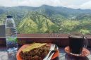 Wisatawan menikmati kopi hangat dan kuliner lokal dengan latar panorama pegunungan hijau di Enrekang, Sulawesi Selatan.