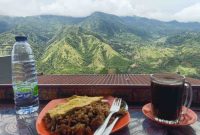 Wisatawan menikmati kopi hangat dan kuliner lokal dengan latar panorama pegunungan hijau di Enrekang, Sulawesi Selatan.