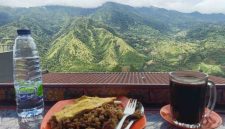 Wisatawan menikmati kopi hangat dan kuliner lokal dengan latar panorama pegunungan hijau di Enrekang, Sulawesi Selatan.