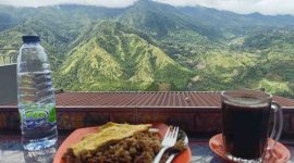 Wisatawan menikmati kopi hangat dan kuliner lokal dengan latar panorama pegunungan hijau di Enrekang, Sulawesi Selatan.