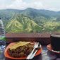 Wisatawan menikmati kopi hangat dan kuliner lokal dengan latar panorama pegunungan hijau di Enrekang, Sulawesi Selatan.