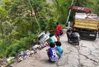 Warga bersama petugas berupaya mengevakuasi mobil yang terjun ke area pembuangan sampah di Jalan Poros Cakke–Baraka, Tinabang, Senin sore.