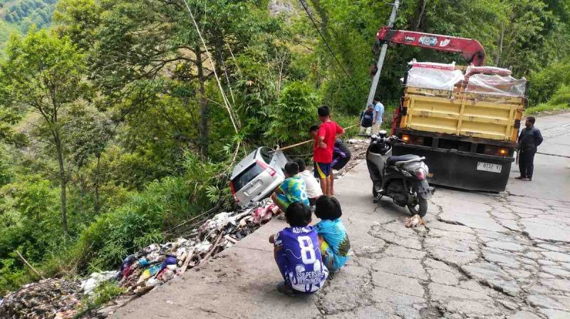 Warga bersama petugas berupaya mengevakuasi mobil yang terjun ke area pembuangan sampah di Jalan Poros Cakke–Baraka, Tinabang, Senin sore.