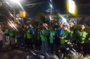 Petugas kepolisian memberikan arahan kepada rombongan pengemudi ojek online sebelum keberangkatan pengawalan menuju Monas pada malam hari.