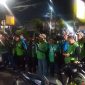 Petugas kepolisian memberikan arahan kepada rombongan pengemudi ojek online sebelum keberangkatan pengawalan menuju Monas pada malam hari.
