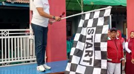 Lurah Kutabumi Ade Sunaryo membuka kegiatan jalan sehat RW 017 dengan mengibarkan bendera start.