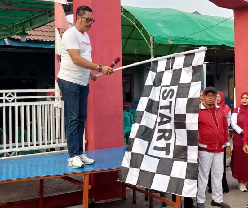 Lurah Kutabumi Ade Sunaryo membuka kegiatan jalan sehat RW 017 dengan mengibarkan bendera start.
