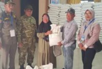 Lurah Pakuhaji Uci Sanusi (tengah) berbaur dan berfoto bersama warga penerima manfaat di sela-sela kegiatan penyaluran bansos beras di Kantor Kelurahan Pakuhaji, Kabupaten Tangerang. (Dok. Dadang). 