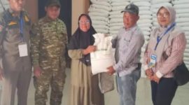 Lurah Pakuhaji Uci Sanusi (tengah) berbaur dan berfoto bersama warga penerima manfaat di sela-sela kegiatan penyaluran bansos beras di Kantor Kelurahan Pakuhaji, Kabupaten Tangerang. (Dok. Dadang). 
