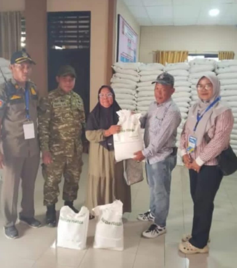 Lurah Pakuhaji Uci Sanusi (tengah) berbaur dan berfoto bersama warga penerima manfaat di sela-sela kegiatan penyaluran bansos beras di Kantor Kelurahan Pakuhaji, Kabupaten Tangerang. (Dok. Dadang). 