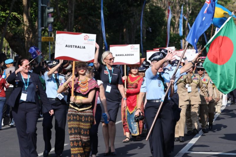 Peserta Parade IAWP 2026 dari berbagai negara berjalan dalam iring-iringan dengan membawa papan nama negara dan mengenakan seragam serta pakaian tradisional masing-masing. Parade berlangsung di kawasan Lapangan Puputan Renon, Denpasar, Bali.